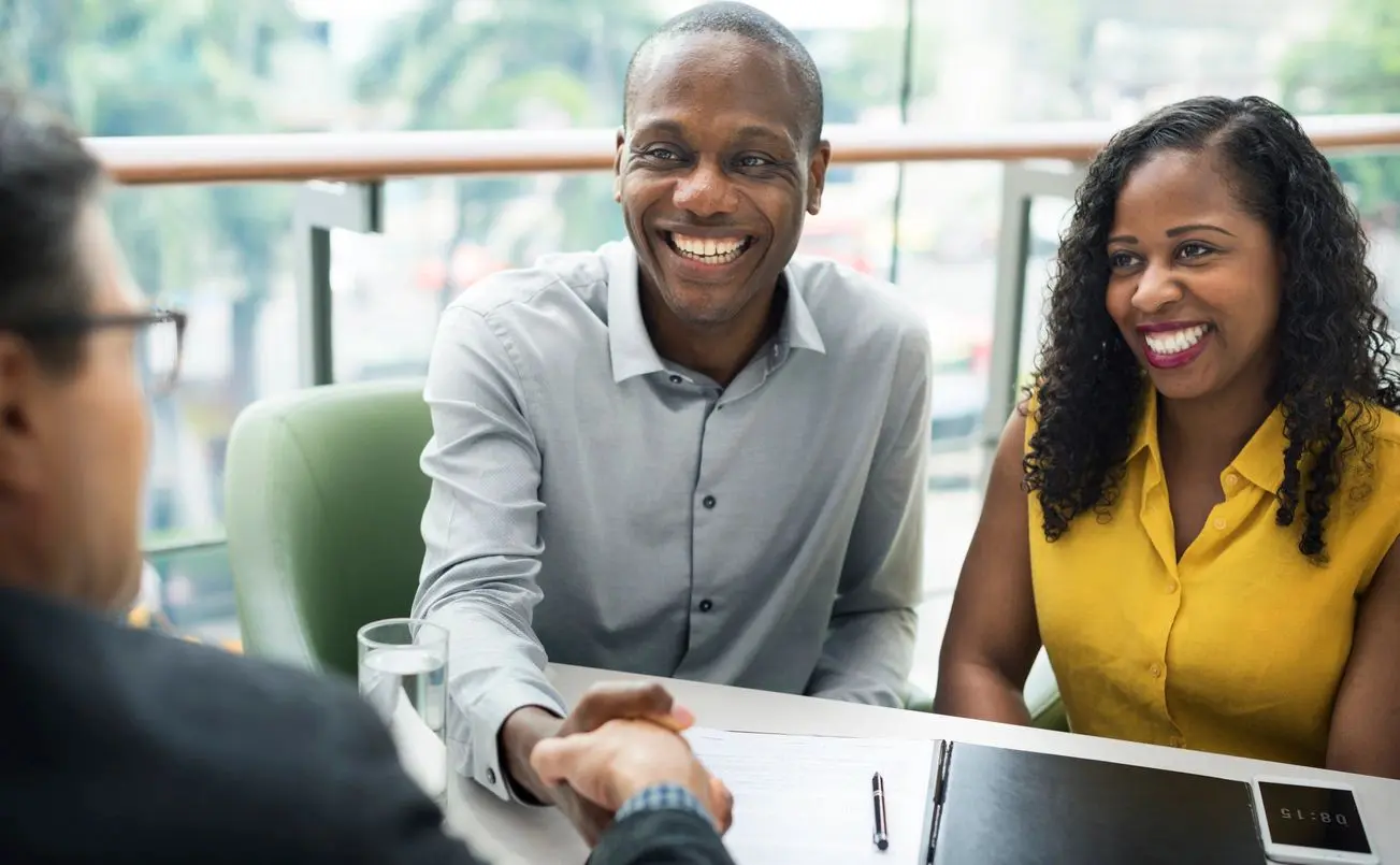 Two professionals shaking hands in a bright office setting.